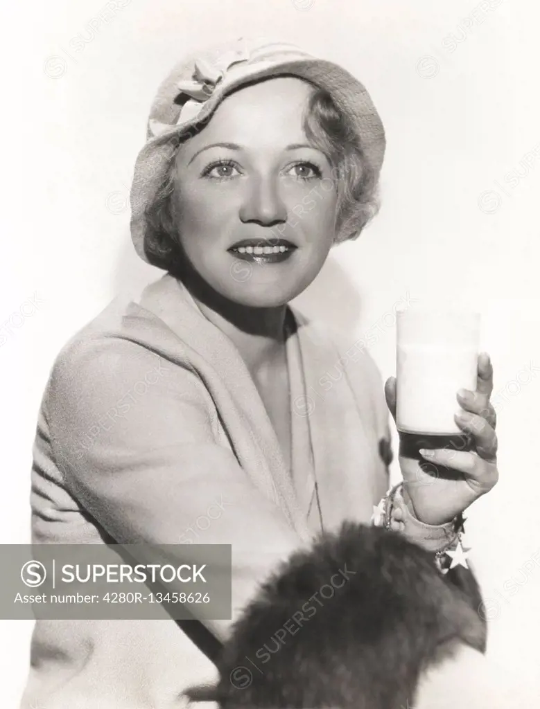 Woman in hat holding a glass of milk