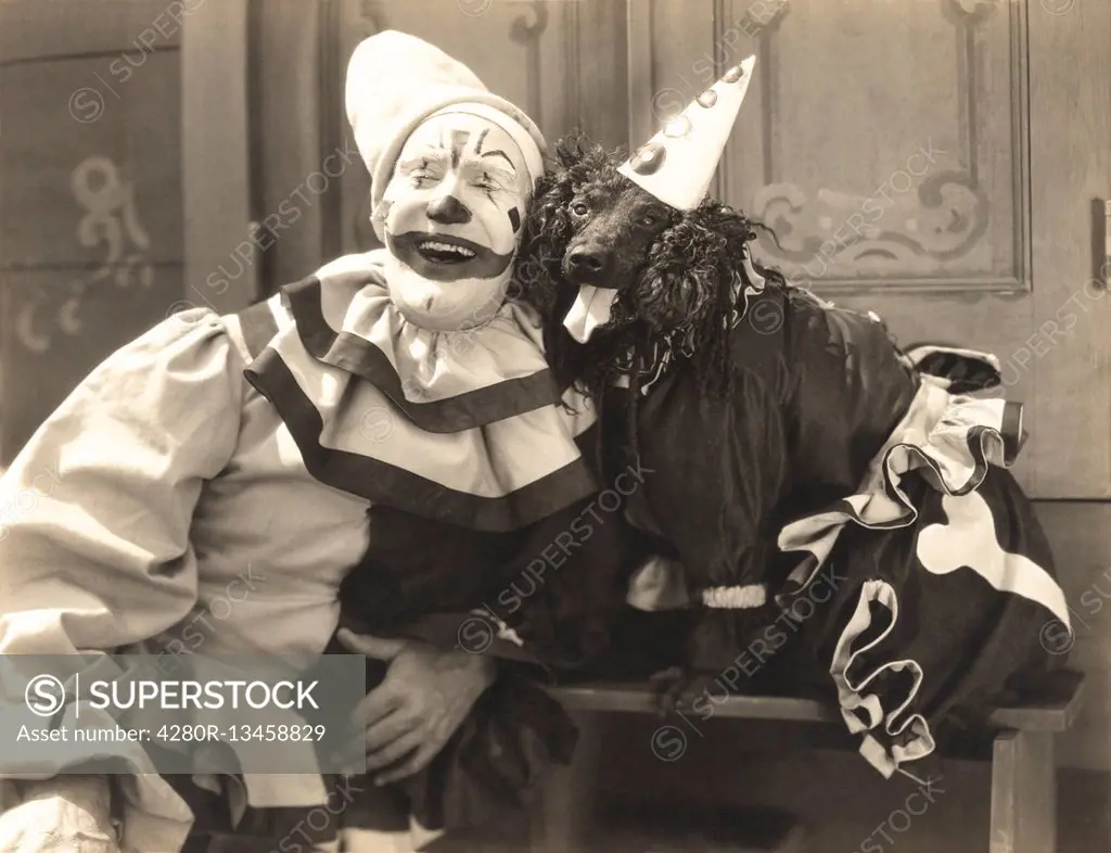 Clown posing with dog dressed in clown costume