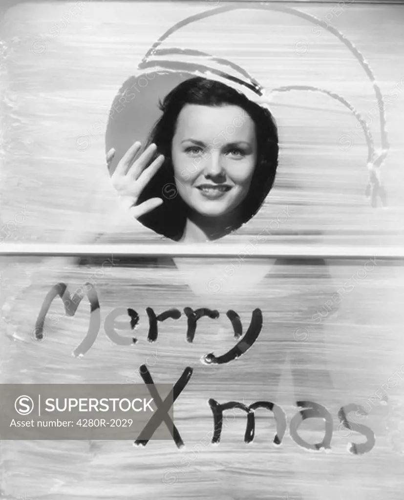 Woman waving at window with Christmas greeting