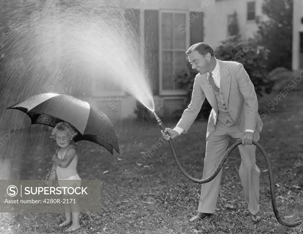 Toddler and dad playing with hose in yard