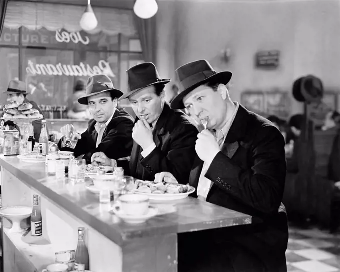 Three men with hats eating at the counter of a diner All persons depicted are not longer living and no estate exists Supplier warranties that there wi...