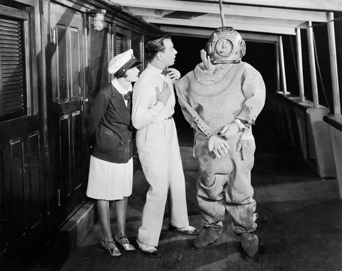 Two people looking in shock at a diver in a divers suit All persons depicted are not longer living and no estate exists Supplier warranties that there...