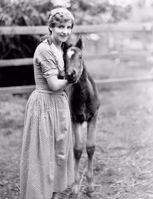 Woman standing next to a pony in a corral All persons depicted are not longer living and no estate exists Supplier warranties that there will be no mo...