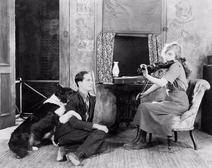 Woman playing the violin for her boyfriend and dog All persons depicted are not longer living and no estate exists Supplier warranties that there will...