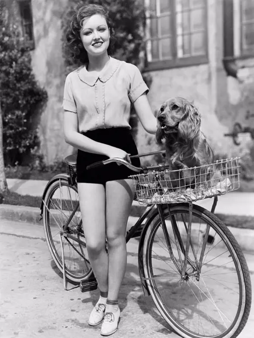 Woman next to her bicycle with her dog in the basket All persons depicted are not longer living and no estate exists Supplier warranties that there wi...