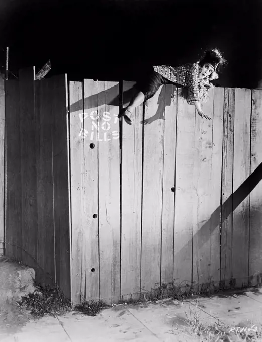 Young woman trying to climb over a wooden fence All persons depicted are not longer living and no estate exists Supplier warranties that there will be...