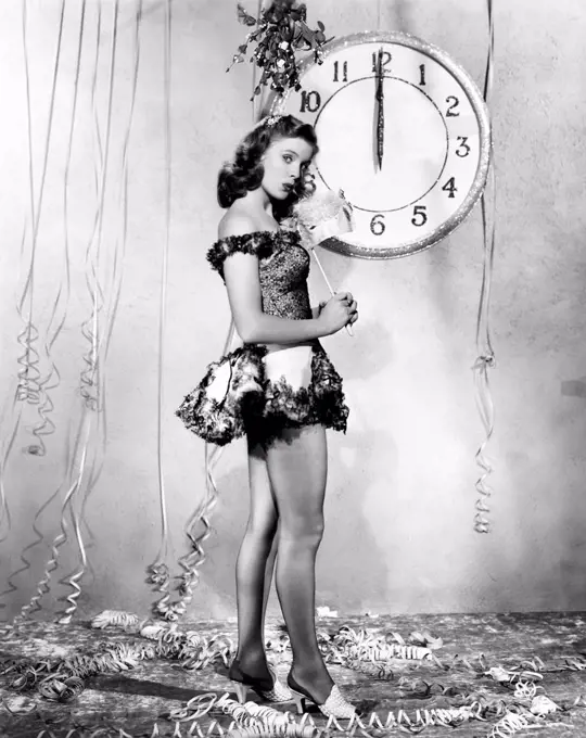 Young woman standing in front of a clock, celebrating New Years Eve All persons depicted are not longer living and no estate exists Supplier warrantie...