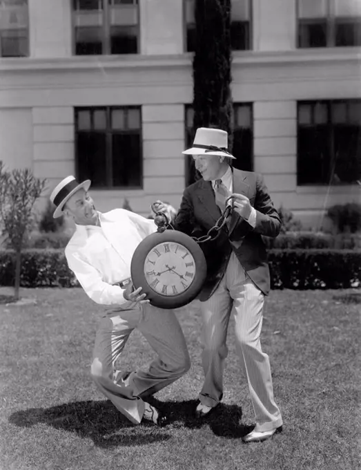 Two men wrestling with an oversized pocket watch All persons depicted are not longer living and no estate exists Supplier warranties that there will b...