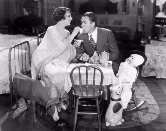 Couple sitting on a toy table having tea together All persons depicted are not longer living and no estate exists Supplier warranties that there will ...