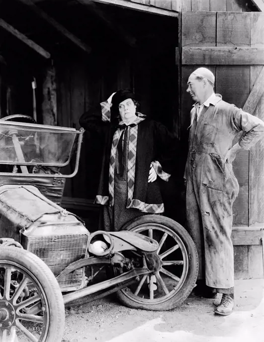 Man and woman looking at a wrecked car in the barn All persons depicted are not longer living and no estate exists Supplier warranties that there will...