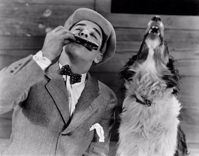 Man playing harmonica with howling dog All persons depicted are not longer living and no estate exists Supplier warranties that there will be no model...