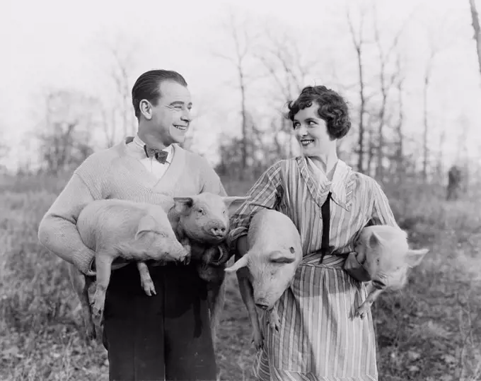 Couple carrying pigs All persons depicted are not longer living and no estate exists Supplier warranties that there will be no model release issues