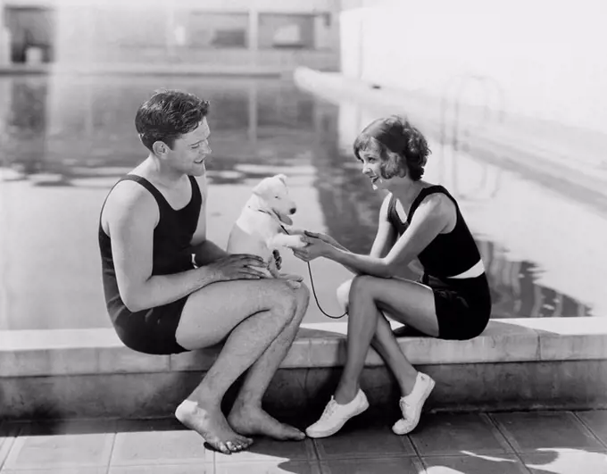 Couple sitting with their puppy next to a pool All persons depicted are not longer living and no estate exists Supplier warranties that there will be ...