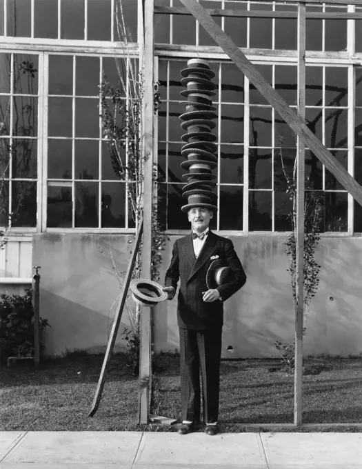 Man standing with stack of hats on head