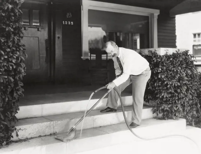 Man moping his front stairs (OLVI008_OU281_F)