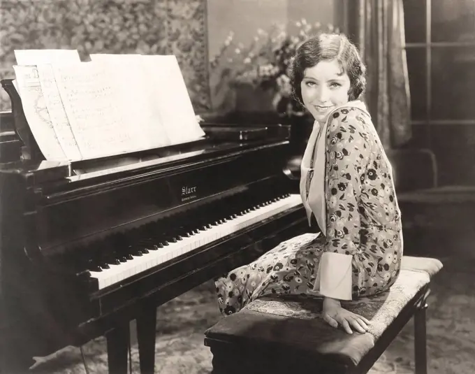 Smiling woman sitting by piano at home