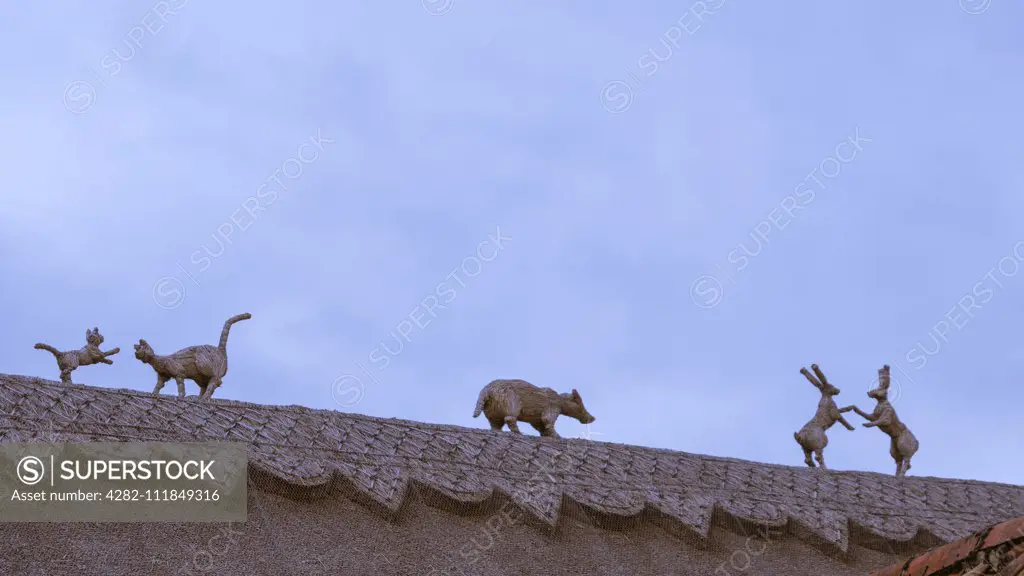 Straw finials of animals on a thatched roof.