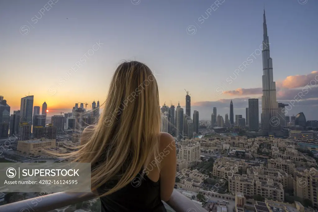 A woman peers off the balcony of her apartment in Dubai.