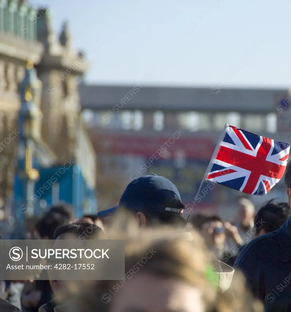 England, London, Westminster. A tour guide with tourists holding a union flag up in central London.