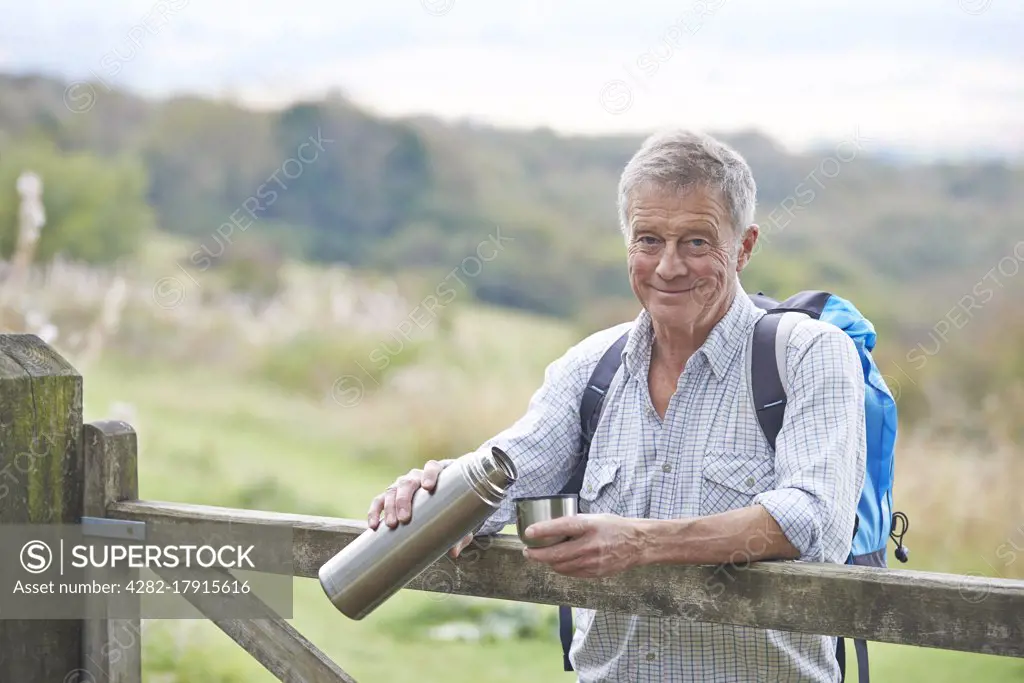 Senior Man Having Drink From Flask Whilst On Walk