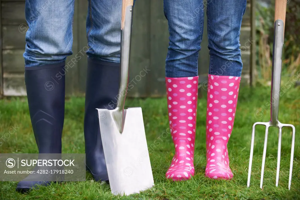 Close Of Couple Gardening Holding Spade And Fork