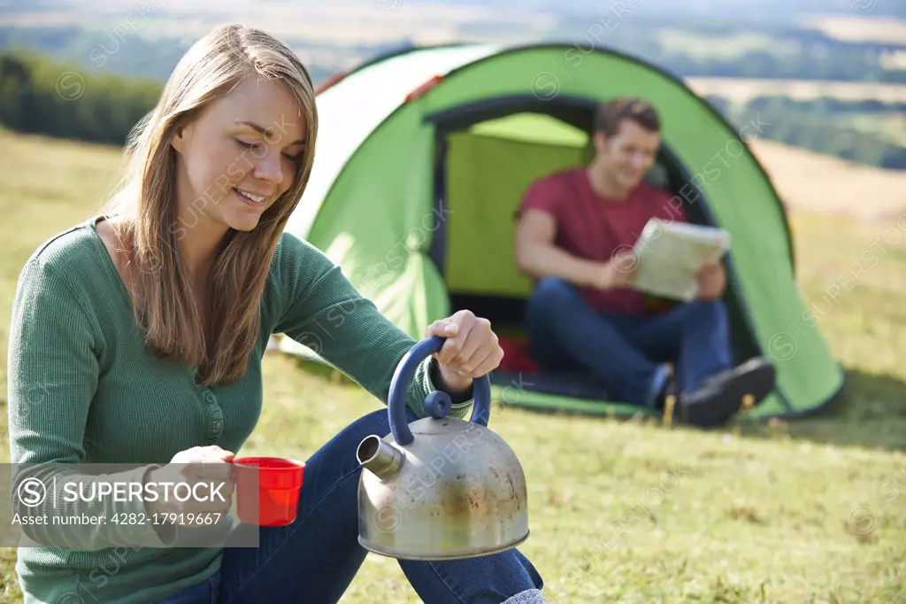 Couple Making Hot Drink Whilst Camping In Countryside