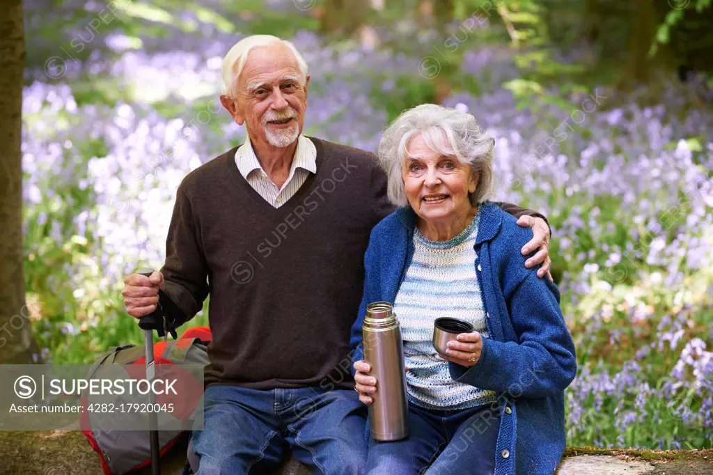 Senior Couple Having Break On Walk Through Bluebell Wood