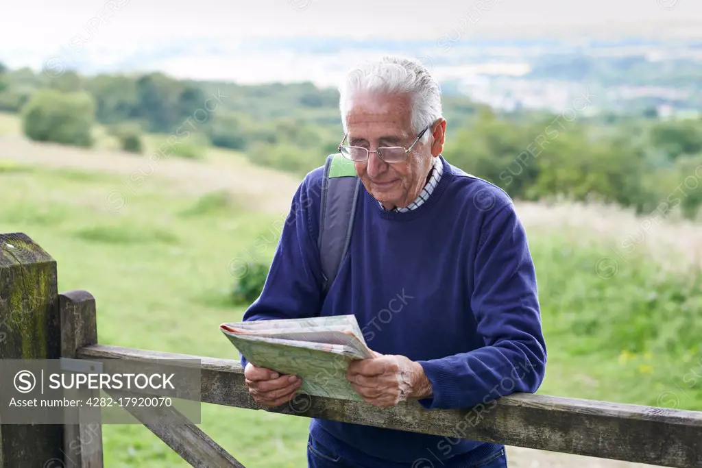 Senior Man Hiking In Countryside Looking At Map