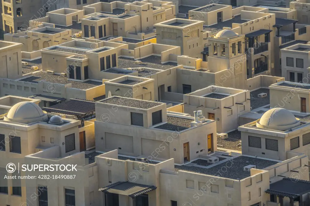 Elegant adobe-style homes beneath the towering gaze of the nearby Burj Khalifa in Dubai.