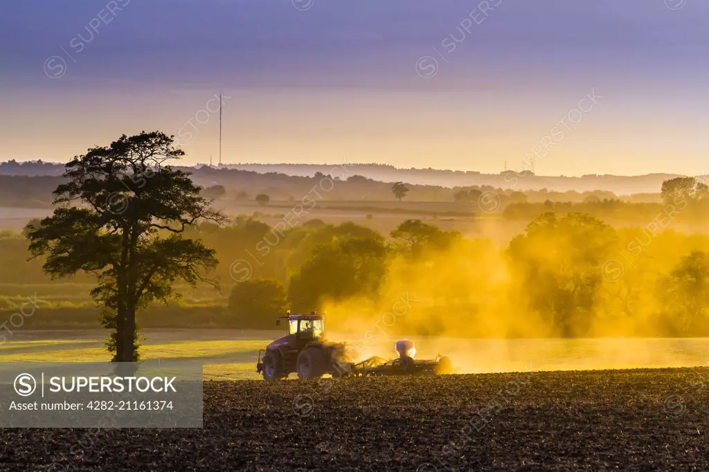 A farmer hard at work as the sun dips low in the sky.