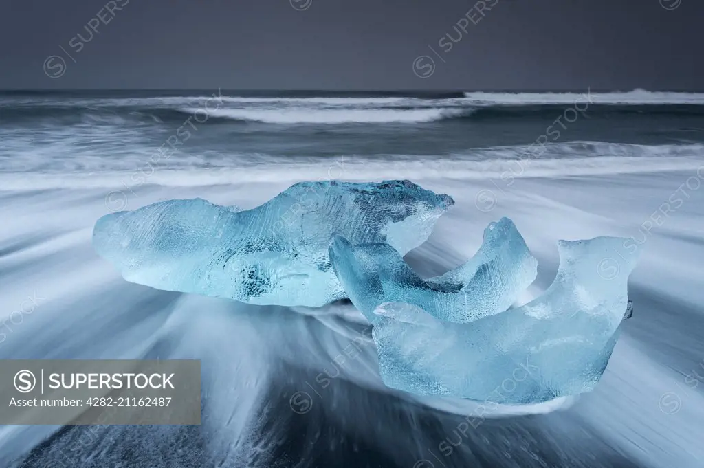 Waves washing around icebergs on the beach at Jokulsarlon in Iceland.