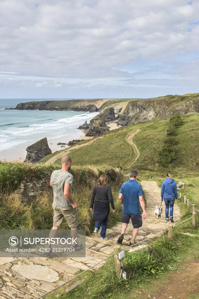 Tourists walk along the South West Coastal Path towards Bedruthan Steps in Cornwall.