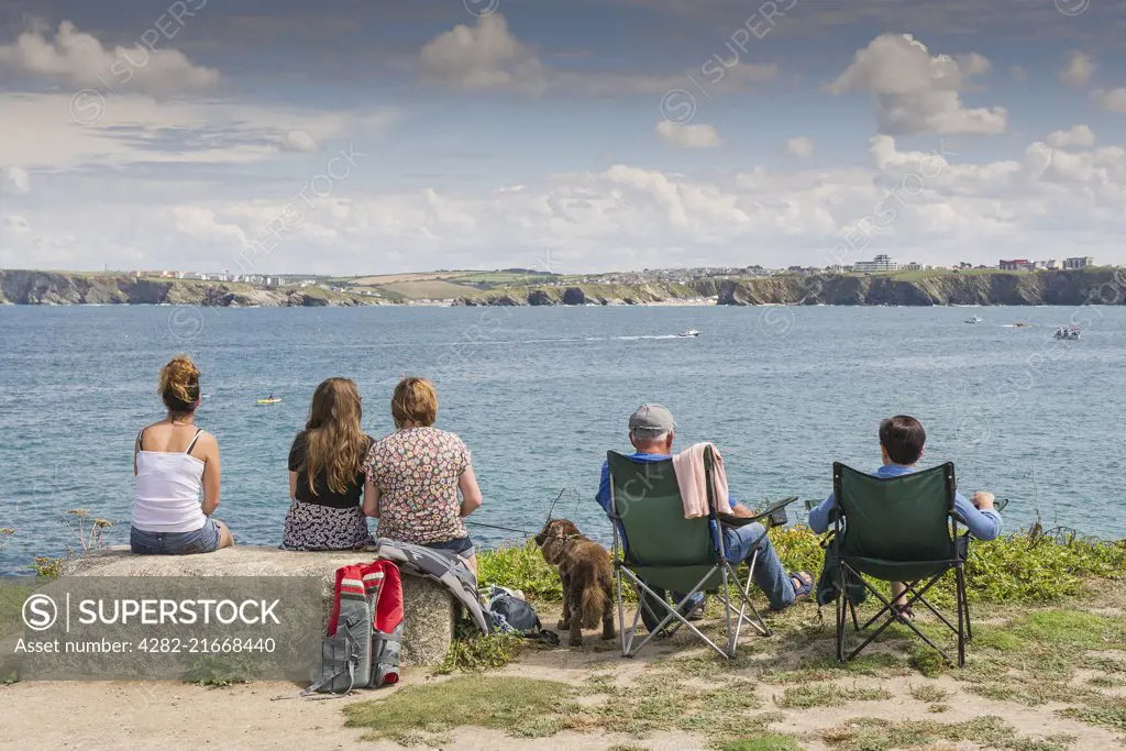 Holidaymakers sit and relax as they look out over the sea at Newquay in Cornwall.