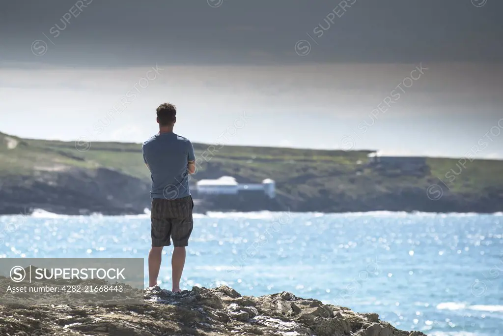 A holidaymaker stands on The Headland in Newquay looking out to sea.