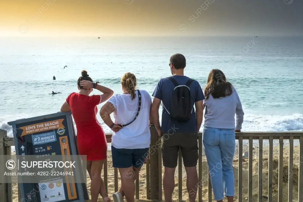 Holidaymakers standing looking out over Fistral Beach in Newquay in Cornwall.