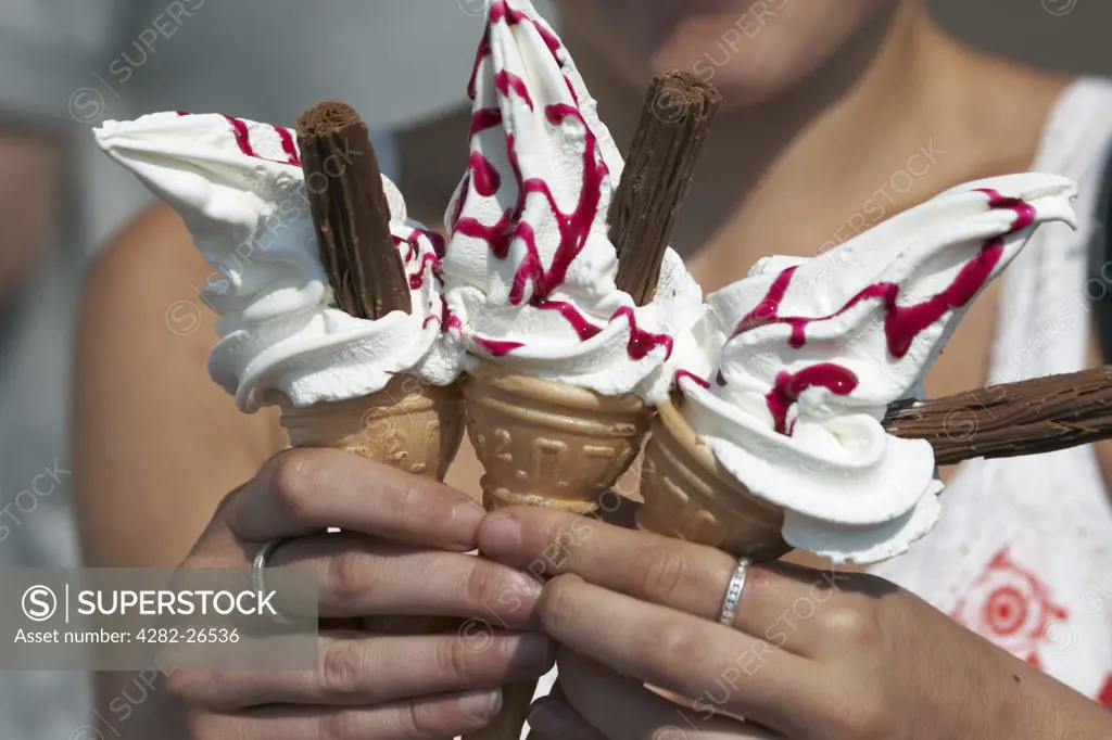 England, Lancashire, Morecambe. A close up of a woman holding three ice cream cones on the sea front at Morecambe.