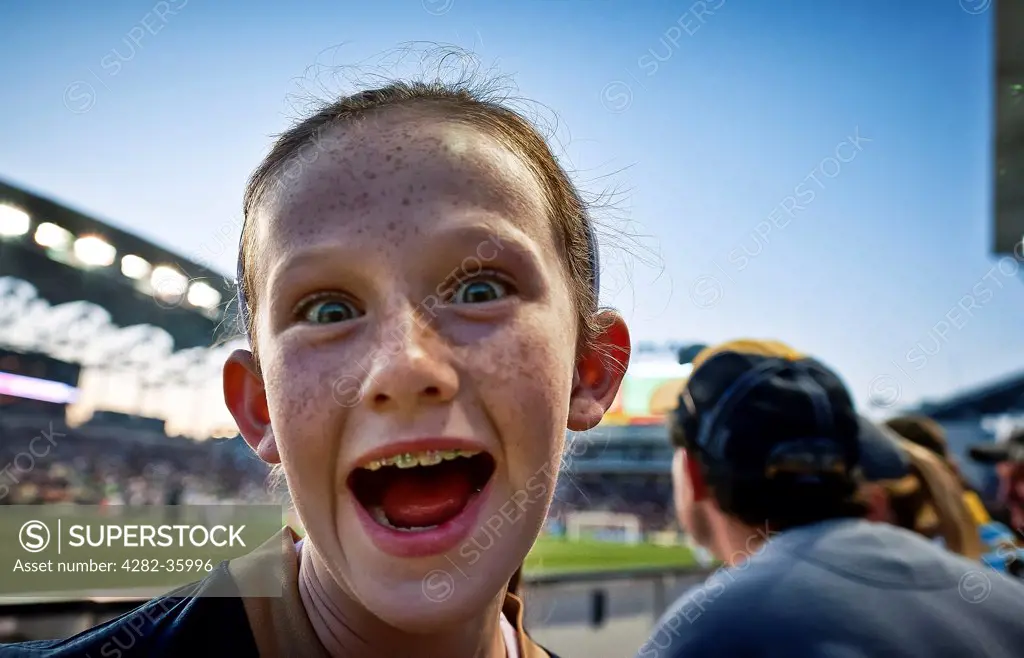 USA, Pennsylvania, Philadelphia. A young girl pulling a funny at a football match.