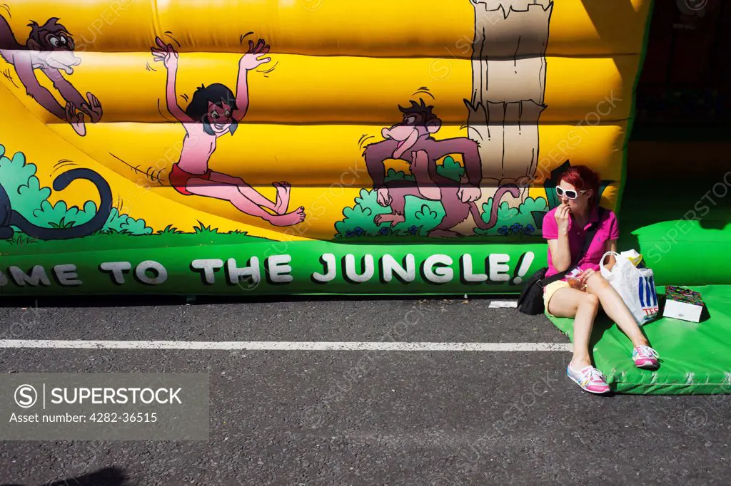 England, Bristol, Bristol. Girl seated by a funfair.