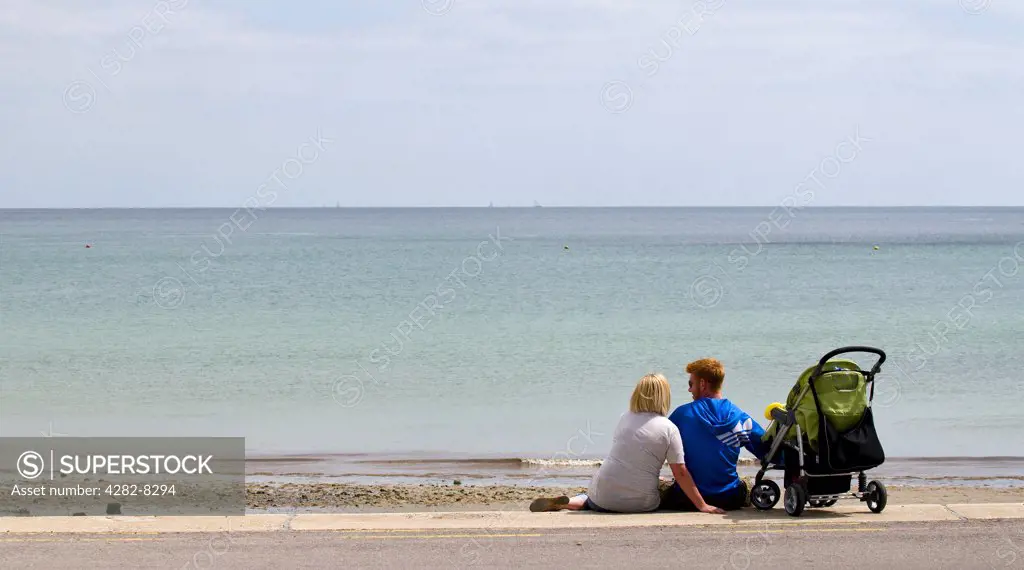 England, West Sussex, Bognor Regis. A young family sitting together on the seafront at Bognor Regis.