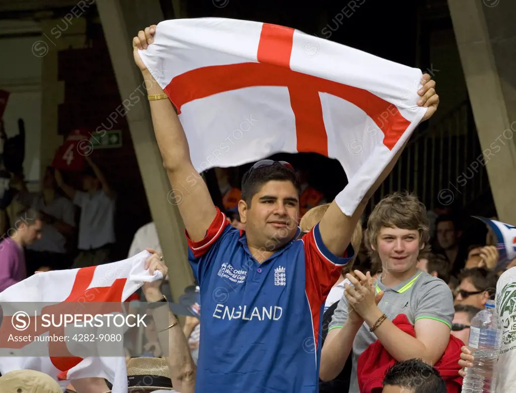 England, London, London. An England cricket fan supporting his team by holding a St George's flag aloft.