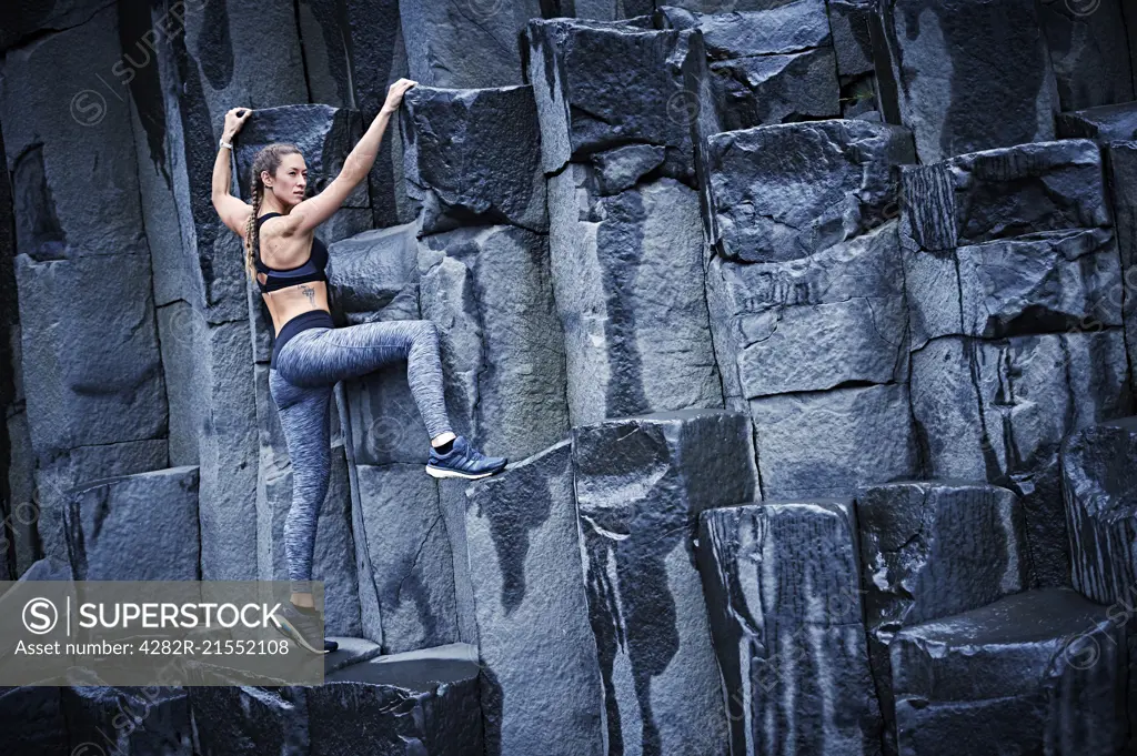 Happy confident young women climbing on basalt rock in southern Iceland.