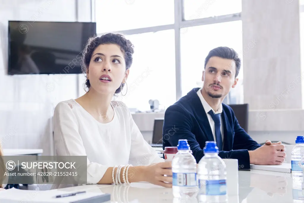 Two young professional people sitting in an office environment during a production meeting.