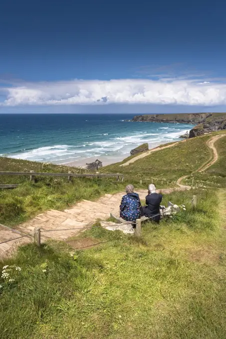 A mature couple sitting and enjoying the spectacular view over Bedruthan Steps at Carnewas in Cornwall.