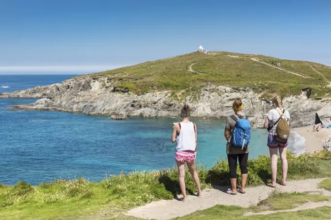 Holidaymakers standing and looking out over the turquoise coloured sea at Little Fistral in Newquay in Cornwall.