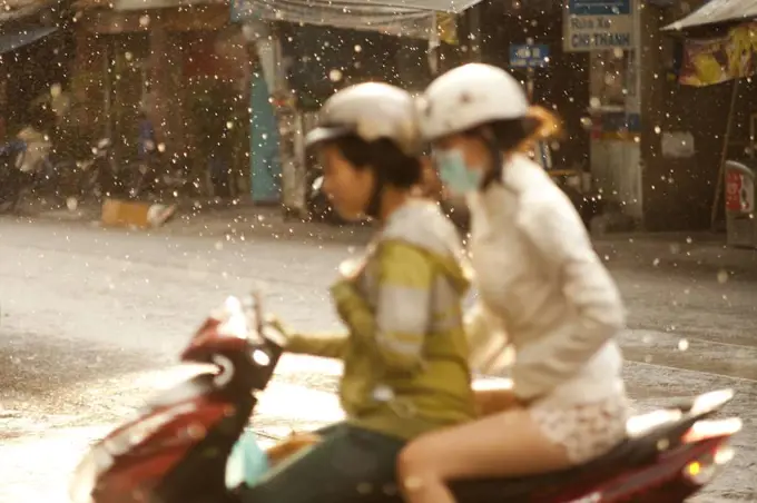 Two women share a moped during a rainstorm on the streets of Ho Chi Minh City in Vietnam.