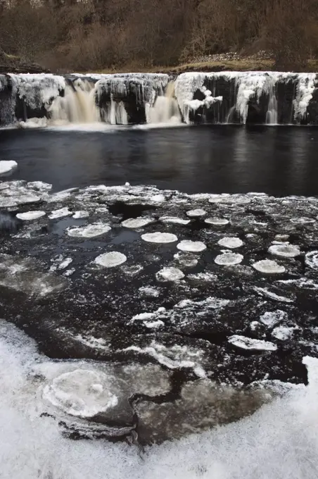 England, North Yorkshire, Upper Swaledale. Wain Wath Force on the River Swale, frozen in winter, in the Yorkshire Dales National Park.