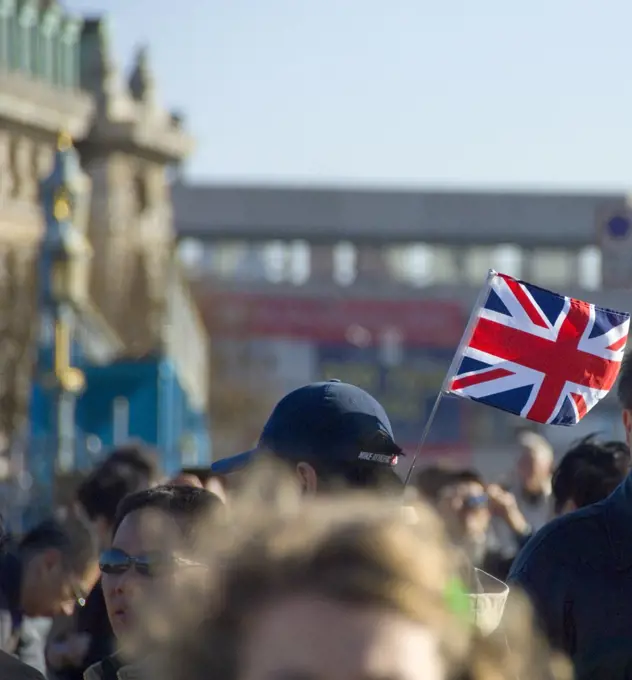 England, London, Westminster. A tour guide with tourists holding a union flag up in central London.