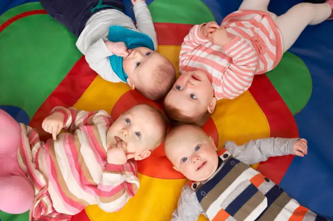 Overhead View Of Babies Lying On Mat At Playgroup