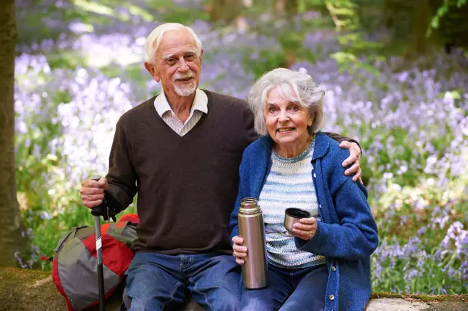 Senior Couple Having Break On Walk Through Bluebell Wood