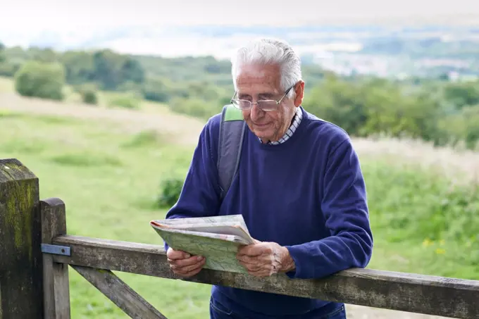 Senior Man Hiking In Countryside Looking At Map